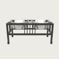 Load image into Gallery viewer, Elevated pet feeder with two metal bowls on a black stand.
