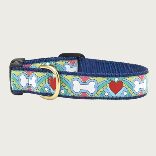 Dog collar with multicolored 60's-style pattern featuring dog bones & red hearts. Inner webbing is navy blue and the collar has a black plastic clip with brass D-ring.