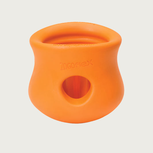 Tangerine (orange) colored Toppl toy. It has a cupped shape, with a slight indent on the top 1/3 of the toy, just under its lip. There is a round opening in the center, and the top of the toy is completely open. There are vertical ridges inside it.