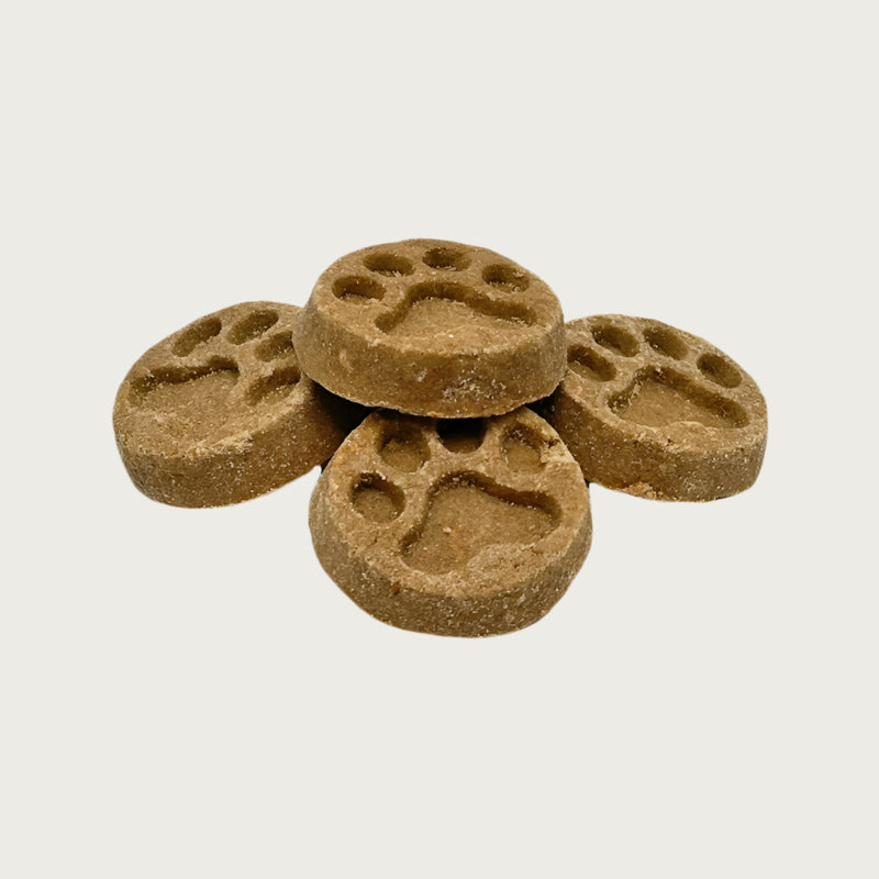 Closeup of five Wet Nose Apple Honey Paw Print treats. They are brown, round, about 2" wide, and embossed with a paw print shape.