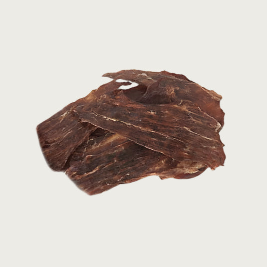 Closeup photo of a small pile of Wet Nose Buffalo Jerky dog treats. Product is varying sizes of rectangular shaped, thin brown strips, ranging from approximately 3" - 6" long.