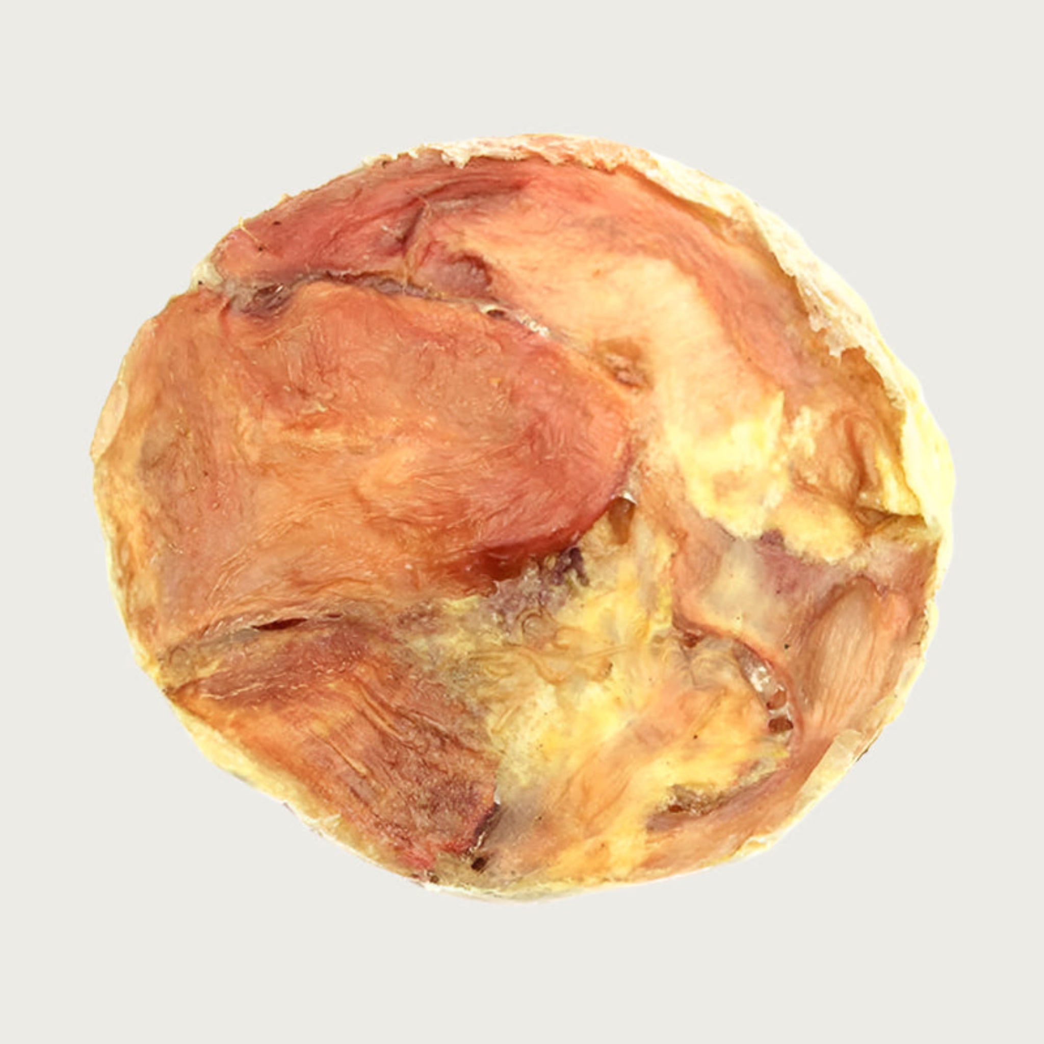 A round, flat dog chew in varying shades of tan and reddish brown.