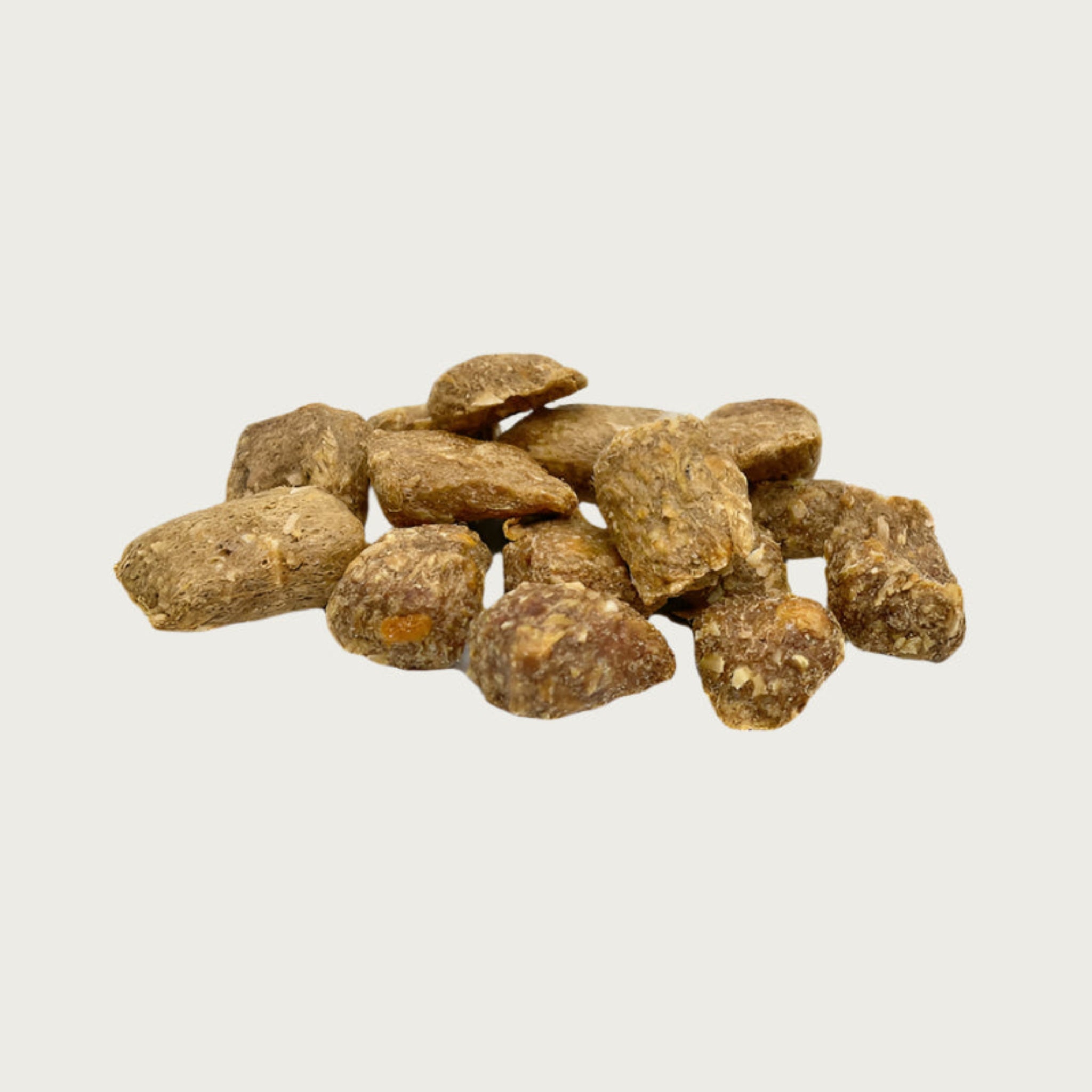 A close-up photo of a small pile of Wet Nose Bunny Drops dog treats. They are pale brown in color, and shaped like pebbles of various sizes, from 0.5" - 1.5" long.