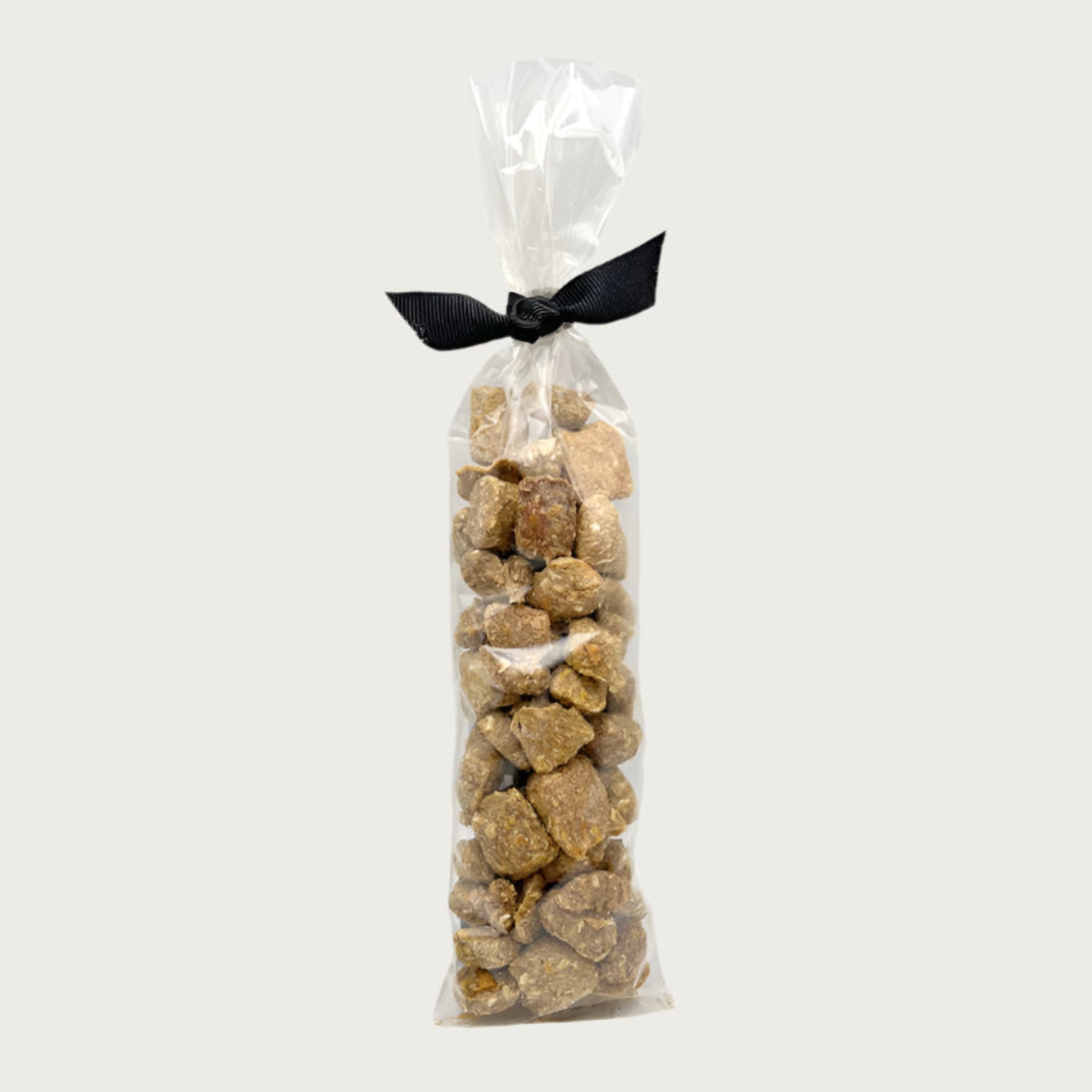 2.25 oz clear cellophane, tube-shaped bag of Wet Nose exclusive Bunny Drops dog treats, tied with black ribbon. Treats inside are pale brown in color, and shaped like pebbles of various sizes.