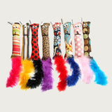 This toy has a simple, rectangular shaped canvas body with feather tail, and flat, screen printed "googly" eyes. Photo shows a group of 8 catnip squirrel toys, showing a variety of colored patterns and colored feather tails.