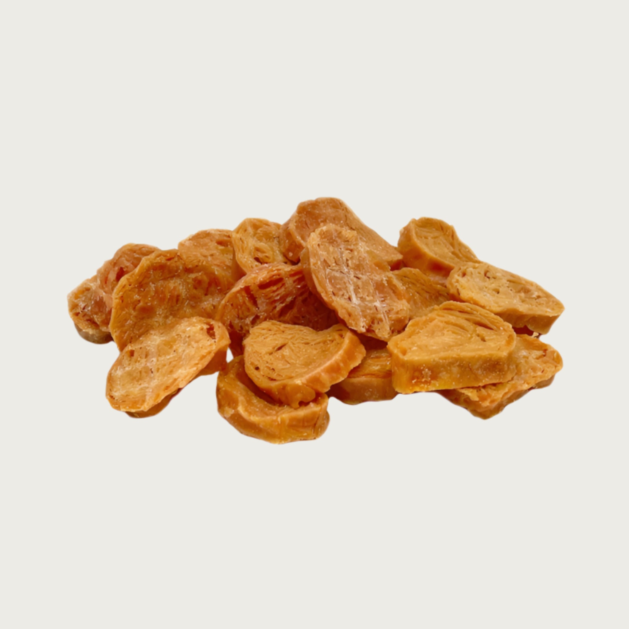 A close-up photo of a small pile of Wet Nose Chicken Nuggets dog treats. They are coin-shaped, round discs, about 1.5" wide, and a pale orangey-tan color.