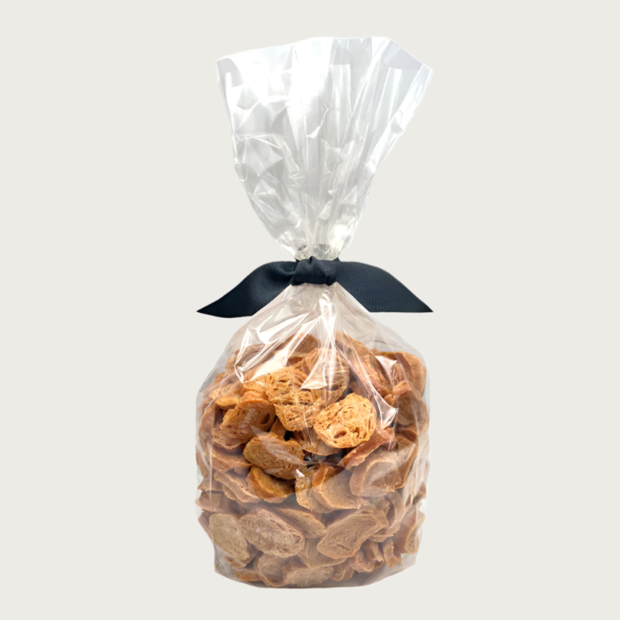 1 lb clear cellophane bag of Wet Nose exclusive Chicken Nuggets dog treats, tied with black ribbon. Coin-shaped treats inside are a pale orangey-tan color.