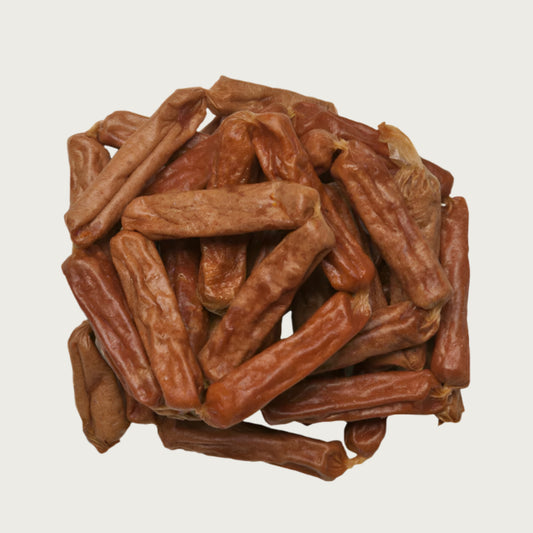 Close-up photo of a small stack of Wet Nose Chicken Smokies dog treats. They are light brown colored links, measuring about 2.5" long.