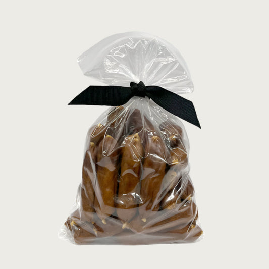 7 oz clear resealable bag of Wet Nose exclusive, Duck Smokies dog treats, tied with black ribbon. Product inside is medium brown colored links. 