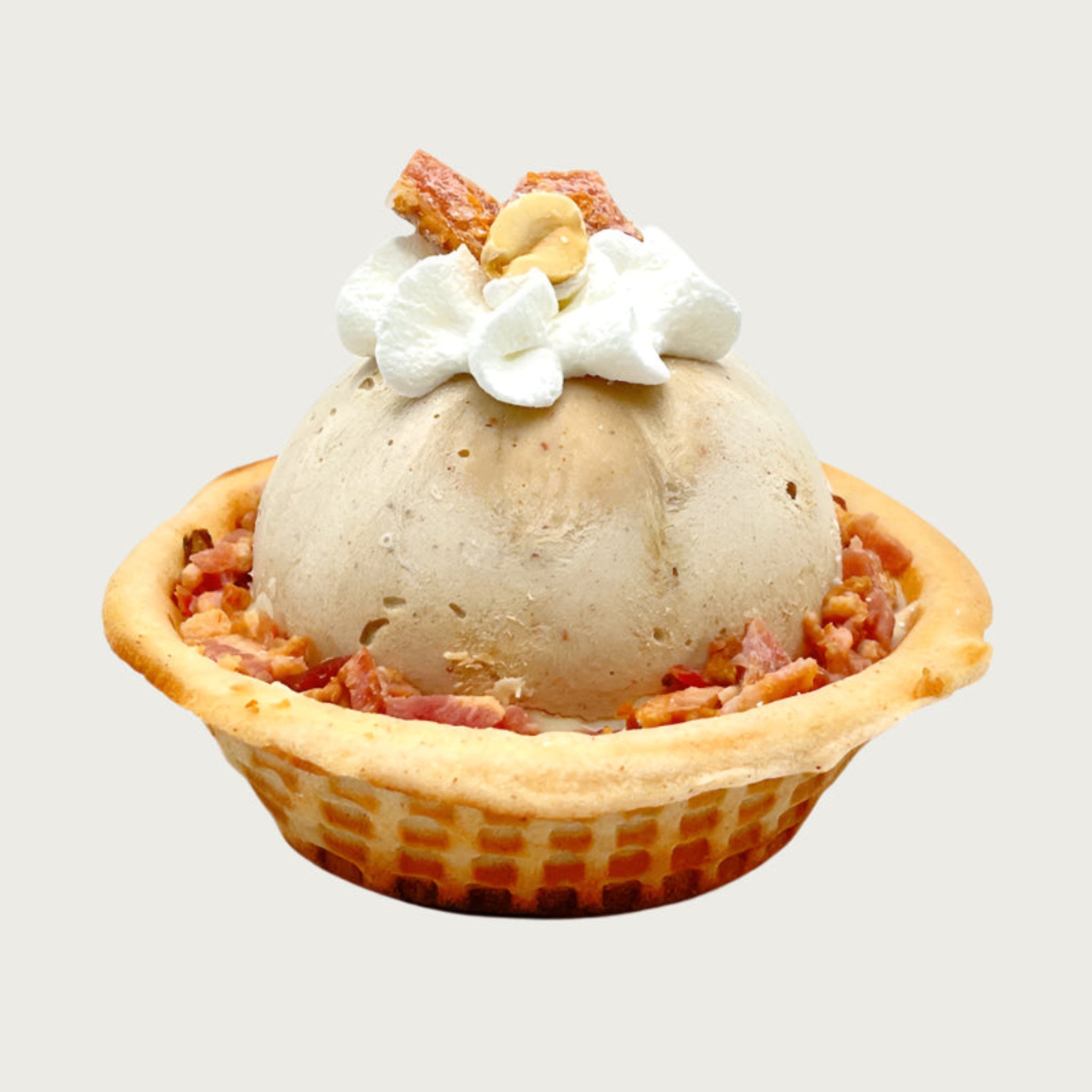 Doggie Ice cream dessert with a scoop of tan colored ice cream in a waffle bowl, topped with a dollop of whipped cream, peanut halves and small pieces of bacon.