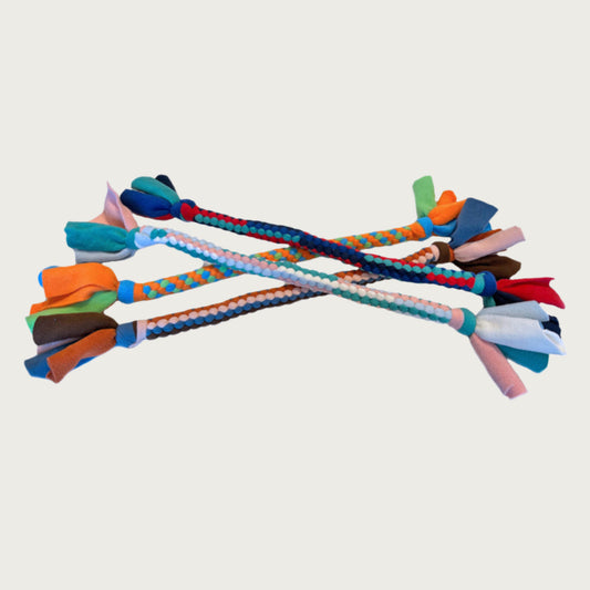 A variety of four large fleece tug dog toys from Wet Nose. They are in a rainbow of color combinations. Toys are tightly knotted & twisted, with thick knots at each end. Loose fleece hangs off the ends like a candy wrapper.