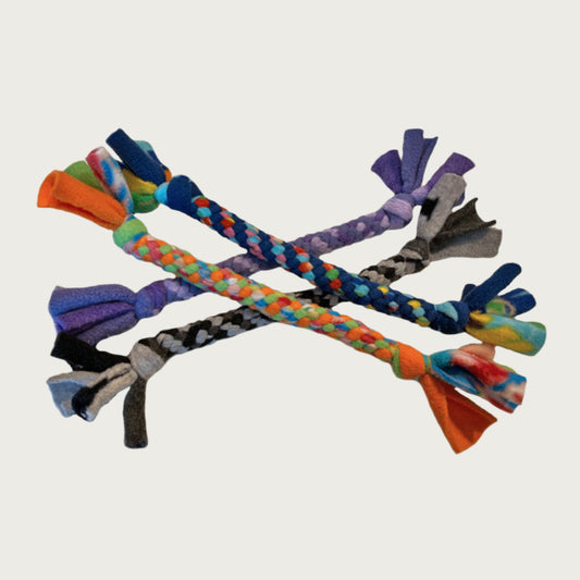 A variety of four small fleece tug dog toys from Wet Nose. They are in a rainbow of color combinations. Toys are tightly knotted & twisted, with thick knots at each end. Loose fleece hangs off the ends like a candy wrapper.
