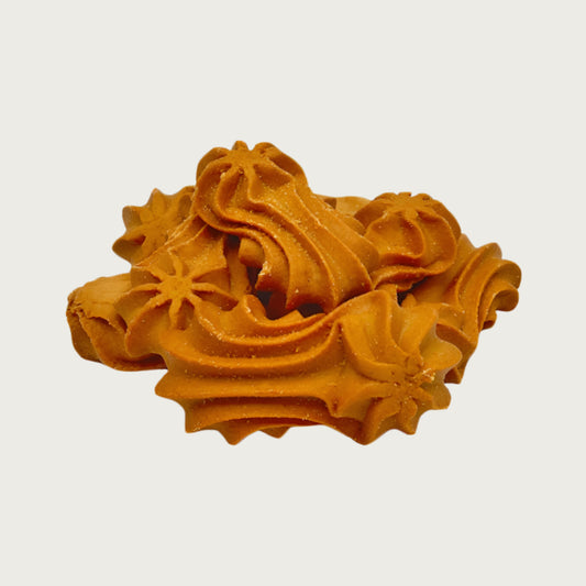Closeup of a small pile of Wet Nose Goobers dog treats. They are tan, oblong shaped, and have a swirl texture on top. They measure about 3" long.