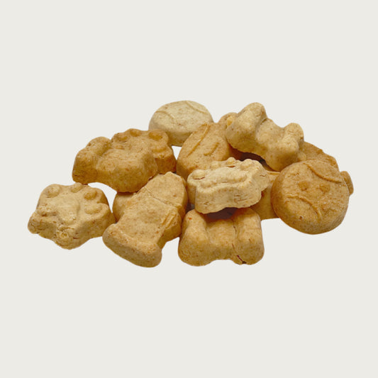 Closeup photo of a small stack of My Favorite Things dog treats. They are tan, and in different shapes; paw print, fire hydrant, dog bone, ball, and food bowl. Each cookie measures about 1" wide.