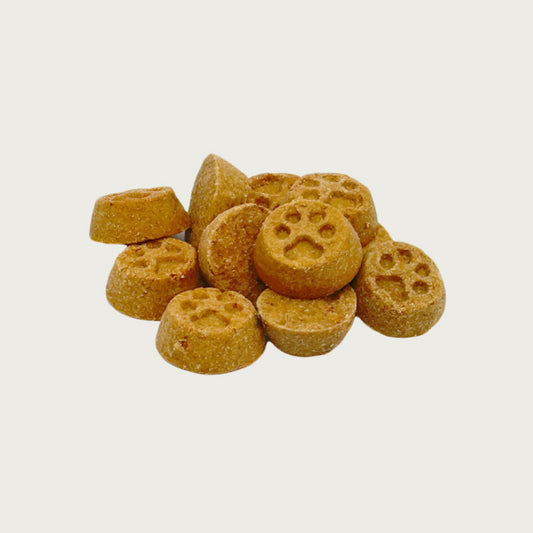 Closeup of a handful of mini paw print treats. They are brown, round, about 0.25" wide and thick, and embossed with a paw print shape.