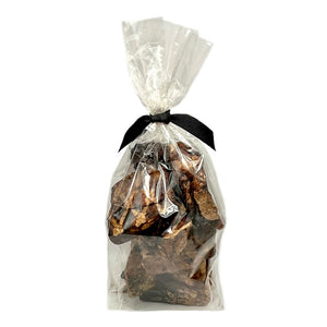 4 oz clear cellophane bag of Wet Nose exclusive Moo Munch dog treats, tied with black ribbon. Product inside is visible; large and small square shaped, brown treats.