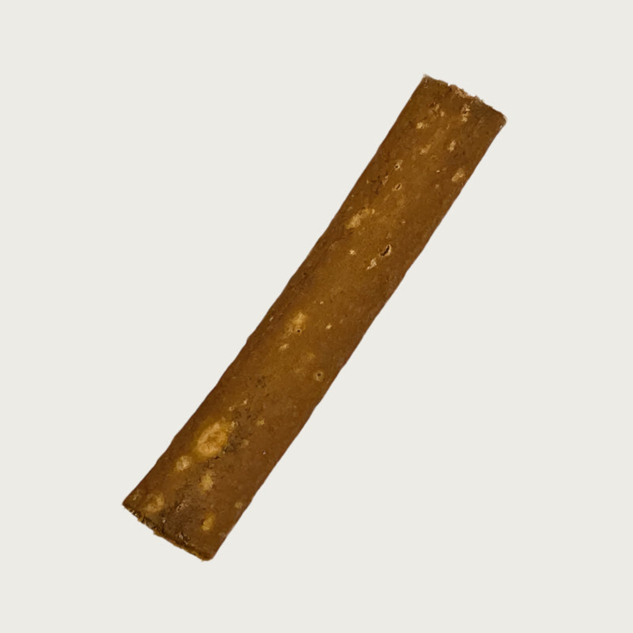 A single piece of ostrich jerky. It is thin, rectangular shaped, and medium brown in color