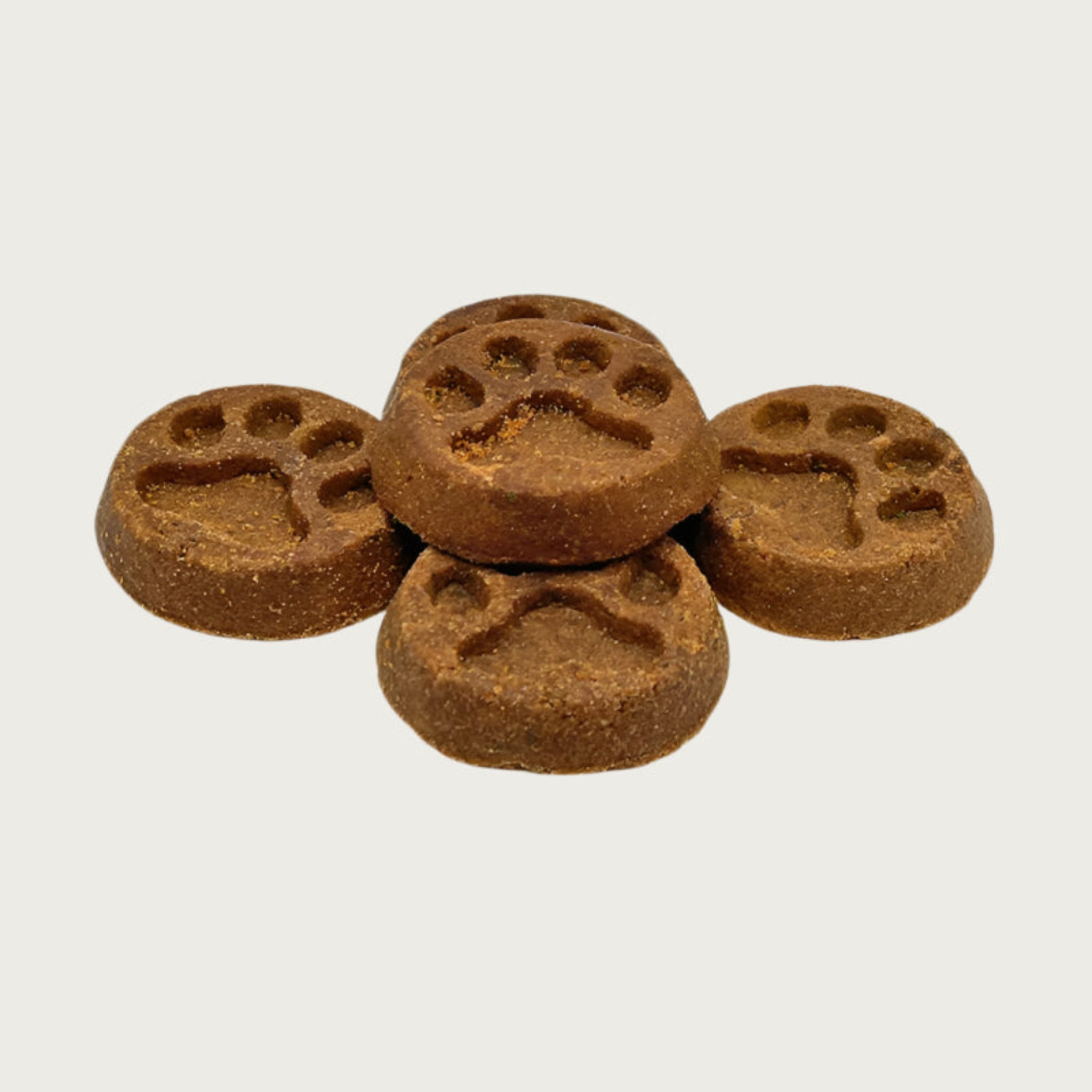 Closeup of five Wet Nose Peanut Butter Paw Print treats. They are brown, round, about 2" wide, and embossed with a paw print shape.