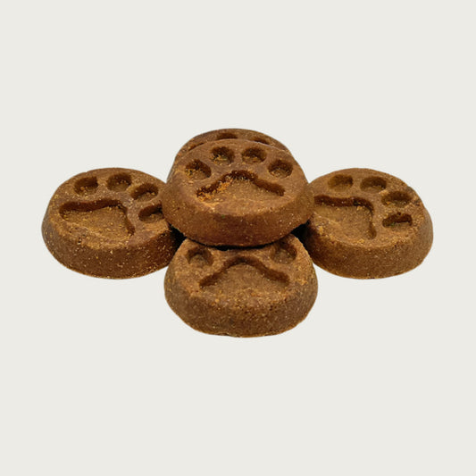 Closeup of five Wet Nose Peanut Butter Paw Print treats. They are brown, round, about 2" wide, and embossed with a paw print shape.