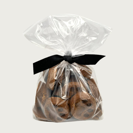 10 oz clear, resealable bag of Wet Nose exclusive, Peanut Butter Paw Print dog treats, tied with black ribbon. Visible inside are 1.5"- 2" sized brown round cookies with embossed paw print.