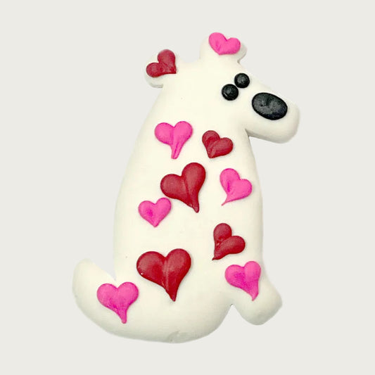 White dog-shaped, cookie for dogs. It is accented with iced red and hot pink heart shapes in various sizes.