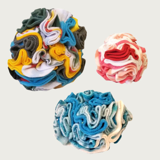 A group of three sizes of Snuffle Ball dog and cat toy from Wet Nose. The balls are fleece, and built with tightly packed folds to hold treats.